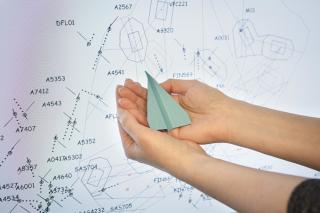 Ihminen paperilennokki käsissään