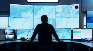 Meriliikennekeskus, jossa meriliikenneohjaaja katsoo seinällä avautuvaa isoa meriliikenteen tilannekuvaa.