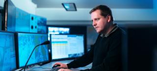 Meriliikennekeskus, jossa suuria monitoreja karttakuvineen sekä yksi meriliikenneohjaaja.