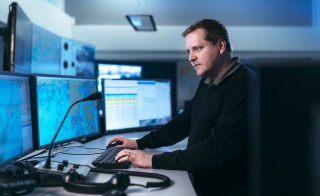 Meriliikennekeskus, jossa suuria monitoreja karttakuvineen sekä yksi meriliikenneohjaaja.