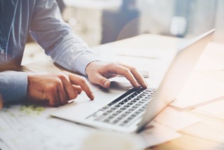 Mies läppärillä, lähikuva käsistä