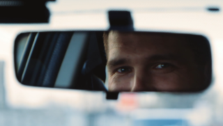Mies katsoo autossa taustapeiliin